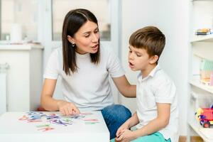 A cute boy with a speech therapist is taught to pronounce the letters, words and sounds. photo