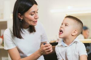 Woman speech therapist helps a child correct the violation of his speech in her office photo