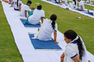 New Delhi, India, June 21, 2023 - Group Yoga exercise session for people at Yamuna Sports Complex in Delhi on International Yoga Day, Big group of adults attending yoga class in cricket stadium photo