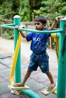 asiático chico haciendo rutina ejercicio en sociedad parque durante el Mañana tiempo. linda pequeño niño ejercicio y gimnasio a mantener él mismo ajuste para vida. niño ejercicio al aire libre disparar foto