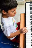 Asian boy playing the synthesizer or piano. Cute little kid learning how to play piano. Child's hands on the keyboard indoor. photo