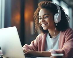 Smiling african american woman in headphones using laptop at home photo