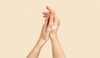 Beautiful young woman hands with cream. Woman applies cream on her hands on beige natural background. Palms with smooth skin on hands, nice natural short nails. Sunscrean spf photo