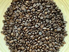 Close up top view background of aromatic brown coffee beans scattered on surface. Coffee beans texture pattern. photo