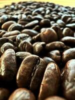 Close up top view background of aromatic brown coffee beans scattered on surface. Coffee beans texture pattern. photo