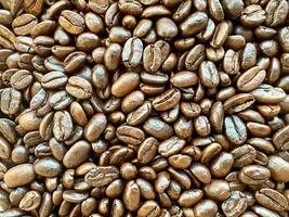 Close up top view background of aromatic brown coffee beans scattered on surface. Coffee beans texture pattern. photo