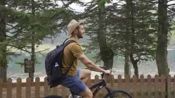 homem equitação bicicleta dentro floresta contra lago visualizar. video