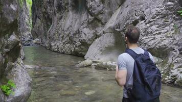 nieuwsgierig jong Mens wandelen langs stroom in Ravijn. video