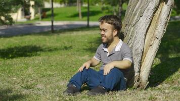 Dwarf young man sitting on the ground excitedly. video