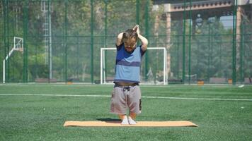 Dwarf young man doing body exercise. She does exercises and stretches outdoors. video