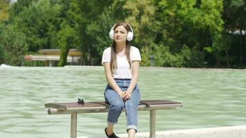 Woman sitting on the ground outdoors listening to sad music and unhappy. video