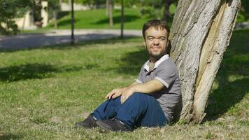 Dwarf young man sitting on the ground and looking at the sky. video