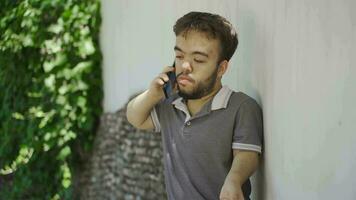 Dwarf young man talking on the phone outdoors. video