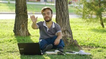 College dwarf student studying outdoors waving at camera. video
