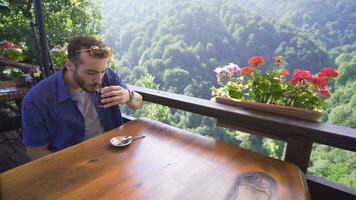 Young man sitting in the terrace cafe of the forest. video