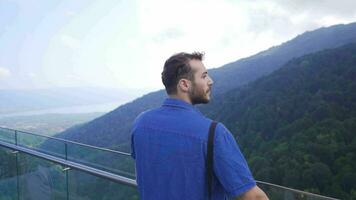 giovane uomo guardare a il canyon su il bicchiere terrazza. video