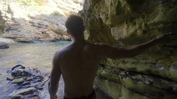 Sporty young man walking in the seaside cave. video
