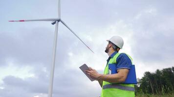 ingeniero utilizando digital tableta en viento turbina granja. video