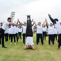 nuevo Delhi, India, junio 21, 2023 - grupo yoga ejercicio sesión para personas a yamuna Deportes complejo en Delhi en internacional yoga día, grande grupo de adultos asistiendo yoga clase en Grillo estadio foto