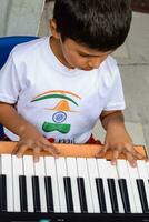 Asian boy playing the synthesizer or piano. Cute little kid learning how to play piano. Child's hands on the keyboard indoor. photo