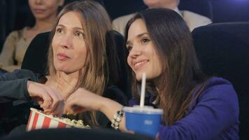 Girl takes popcorn from woman's bucket at the movie theater video