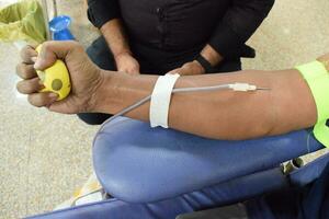 donante de sangre en el campamento de donación de sangre sostenido con una pelota hinchable en la mano en el templo balaji, vivek vihar, delhi, india, imagen para el día mundial del donante de sangre el 14 de junio de cada año, campamento de donación de sangre foto