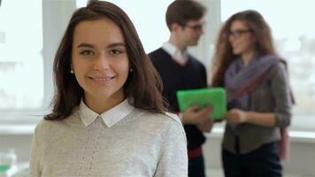 Man and woman look at the tablet behind the smiling girl at the office video