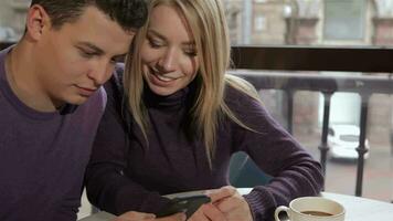 Pareja mira a el del hombre teléfono inteligente café video