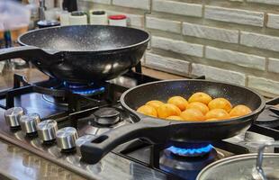 Halves of fresh apricots are fried in caramel syrup in frying pan on gas stove photo