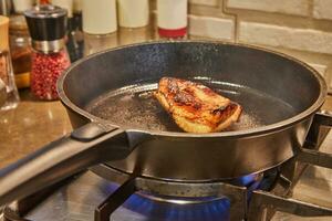 Duck breast is fried in frying pan on gas stove photo