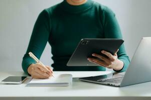Close-up view of young professional businessman writing his idea concepts on notebook while working on his project photo