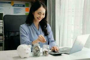 businesswoman holding coins putting in glass with using smartphone and calculator to calculate concept saving money for finance accounting photo