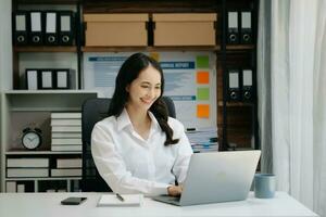 Asian businesswoman hand writing on the notepad with new modern computer strategy diagram as concept morning light photo