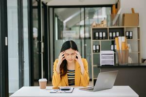 Woman who is tired and overthinking from working with tablet and laptop at modern office. photo