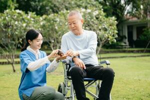 Elderly asian senior woman on wheelchair with Asian careful caregiver and encourage patient, walking in garden. with care from a caregiver photo