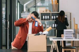 contento y emocionado joven hermosa asiático hombre oficina trabajador celebrando su resignación, que lleva su personal cosa. dejando trabajo, cambiando o compañía. foto