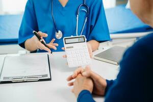 Healthcare costs and fees concept.Hand of smart doctor used a calculator and smartphone, tablet for medical costs at hospital photo