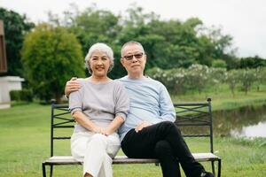 Asian senior couple having a good time. They laughing and smiling while sitting outdoor in park. Lovely senior couple photo
