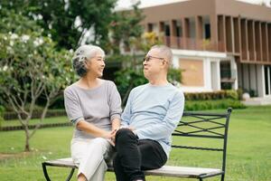 Asian senior couple having a good time. They laughing and smiling while sitting outdoor in park. Lovely senior couple photo