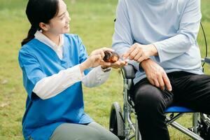 Elderly asian senior woman on wheelchair with Asian careful caregiver and encourage patient, walking in garden. with care from a caregiver photo