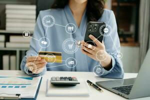 Woman using smart phone for mobile payments online shopping, omni channel, sitting on table, virtual icons graphics interface screen photo