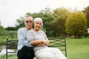 Asian senior couple having a good time. They laughing and smiling while sitting outdoor in park. Lovely senior couple photo