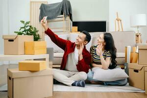 Asian young attractive couple man and woman use tablet and smartphone online shopping furniture decorate house with carton package move in new house. Young married moving home. photo