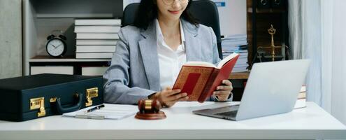 Woman lawyer reading legal book with gavel on table in office. justice and law ,attorney concept. photo