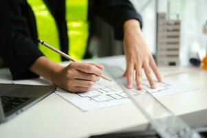 business man hand working and laptop with on on architectural project at construction site at desk in office photo