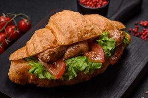 Delicious fresh crispy croissant with chicken or beef meat, lettuce, tomatoes, spices and sauce photo