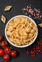 Raw Italian pasta conchiglie from durum wheat with vegetables, salt and spices photo