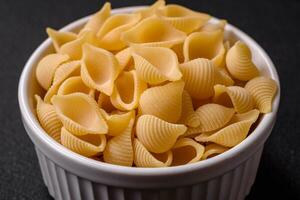 Raw Italian pasta conchiglie from durum wheat with vegetables, salt and spices photo