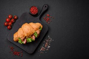 Delicious fresh crispy croissant with chicken or beef meat, lettuce, tomatoes, spices and sauce photo