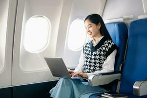 Young Asian executive excels in first class, multitasking with digital tablet, laptop and smartphone. Travel in style, work with grace. in morning light photo